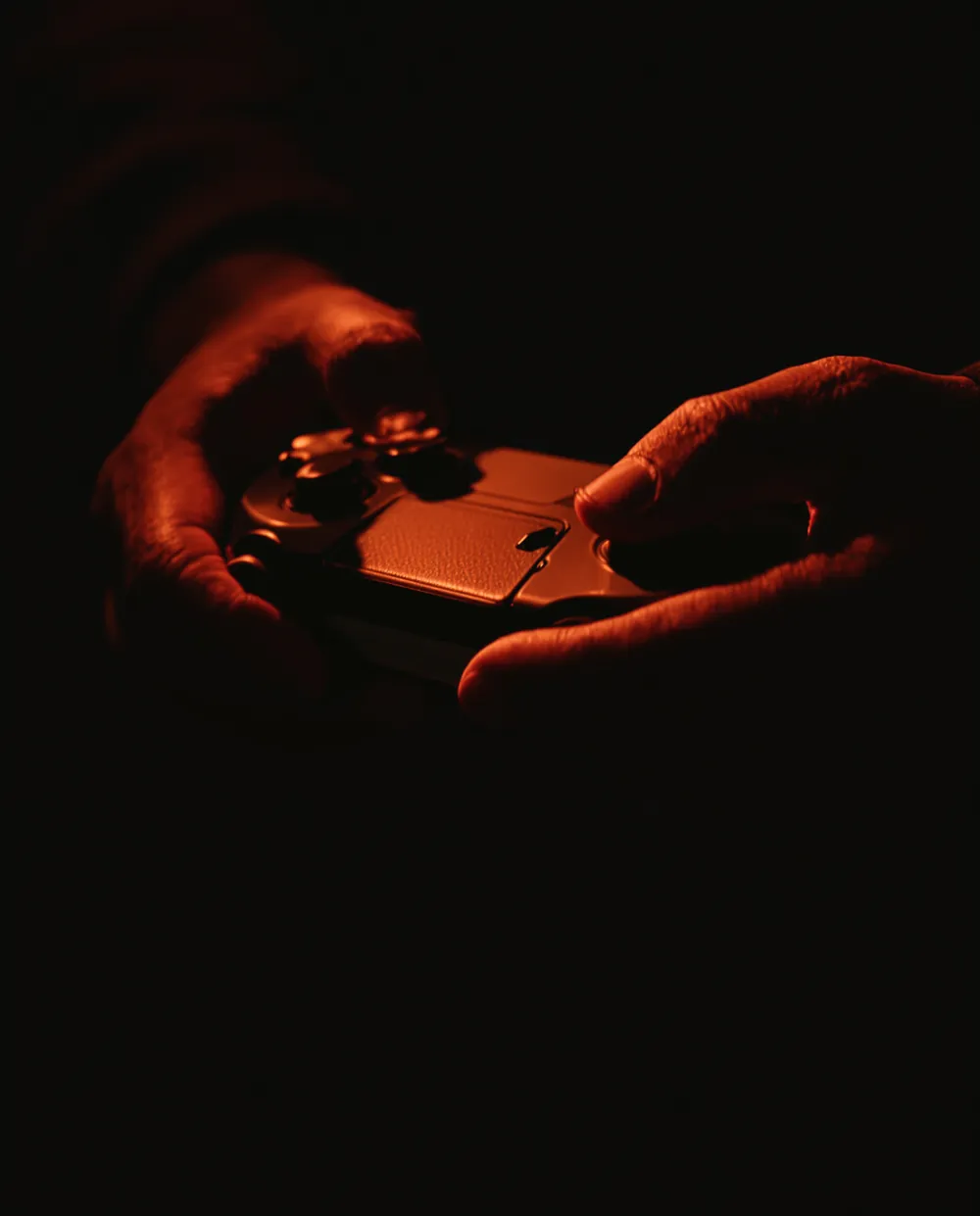 Close de mãos segurando um controle sob luz laranja